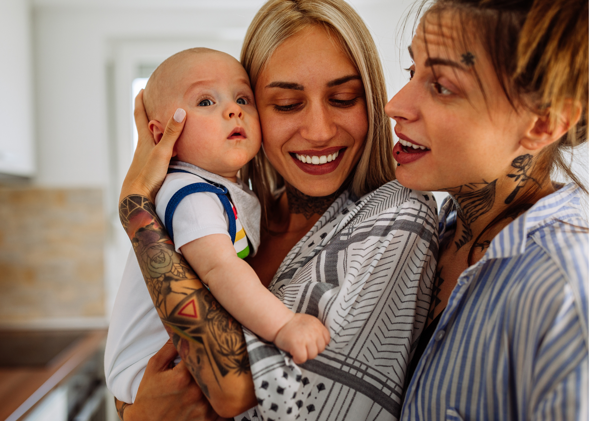 Two mothers smiling with their baby